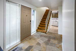 Foyer featuring washing machine and dryer, stone tile flooring, and stairs