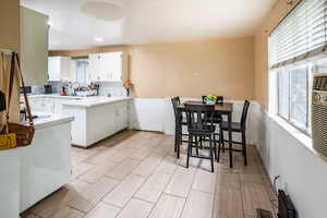 Kitchen with healthy amount of natural light, tile countertops, white cabinets, and light tile floors