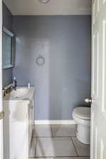Half Bathroom,  tile patterned flooring, vanity, and baseboards