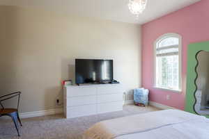 Carpeted bedroom with baseboards and a chandelier