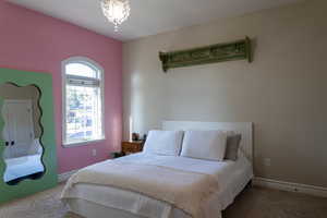 Carpeted bedroom featuring a chandelier and baseboards
