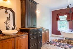 Bathroom with vanity, a freestanding tub, ornamental molding, baseboards, and brick patterned floors