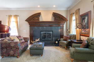 Carpeted living area with crown molding, a tile fireplace, and recessed lighting