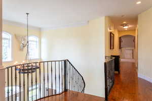 Corridor featuring an upstairs landing, a chandelier, dark wood finished floors, arched walkways, and recessed lighting