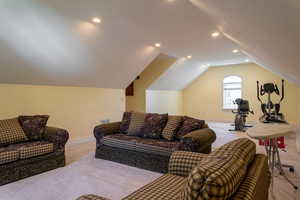 Carpeted living area featuring vaulted ceiling, baseboards, and recessed lighting