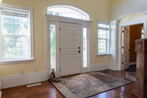 Foyer featuring wood finished floors and decorative columns