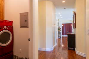 Washroom featuring washer / dryer, electric panel, wood-type flooring, recessed lighting, and baseboards