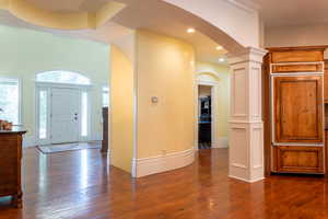 Foyer with arched walkways, dark wood-style flooring, ornate columns, recessed lighting, and baseboards