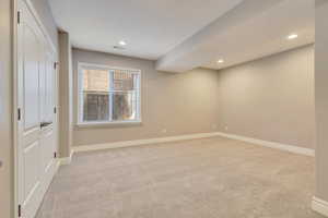 Spare room featuring light colored carpet, baseboards, and recessed lighting