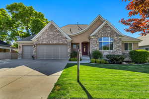Traditional-style home featuring an attached garage, a front yard, driveway, brick siding, and stucco siding