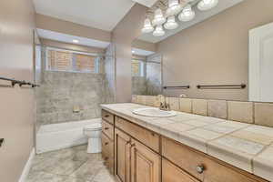 Bathroom with toilet, vanity, tile patterned flooring, bathing tub / shower combination, and baseboards