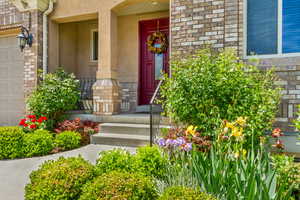 Doorway to property with covered porch, stone siding, stucco siding, and a garage