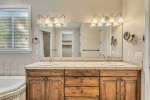 Full bath featuring a bath and double vanity