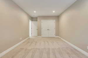 Unfurnished bedroom featuring recessed lighting, baseboards, a closet, and light colored carpet