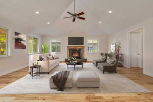 Living room featuring a glass covered fireplace, plenty of natural light, wood finished floors, recessed lighting, and a ceiling fan