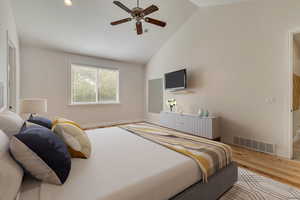 Bedroom featuring wood finished floors, baseboards, high vaulted ceiling, and ceiling fan