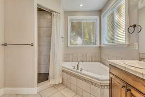 Bathroom featuring tile patterned floors, a tub with jets, a stall shower, and healthy amount of natural light