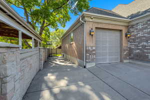 View of side of property with an attached garage, concrete driveway, fence, roof with shingles, and stucco siding