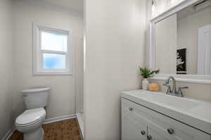 Bathroom featuring baseboards, vanity, toilet, and crown molding