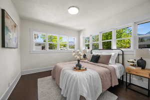 Bedroom with multiple windows, baseboards, wood finished floors, and a textured ceiling