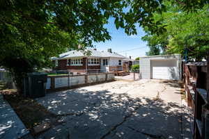Ranch-style home with a fenced front yard, an outdoor structure, concrete driveway, and brick siding