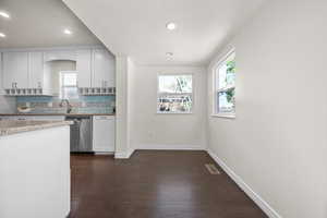 Kitchen featuring stainless steel dishwasher, plenty of natural light, dark wood finished floors, tasteful backsplash, and recessed lighting