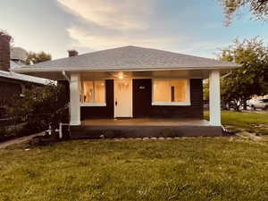 View of front of house with covered porch and a front lawn