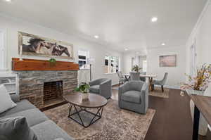 Living room featuring crown molding, recessed lighting, wood finished floors, a fireplace, and baseboards