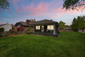 Back of house featuring a chimney, brick siding, and covered porch