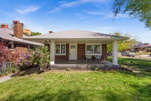 Bungalow-style house featuring covered porch, brick siding, and a chimney