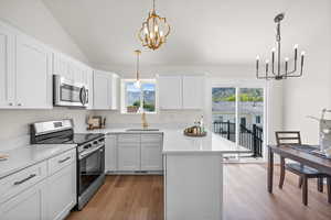 Kitchen with appliances with stainless steel finishes, a chandelier, a sink, light wood-style flooring, and plenty of natural light