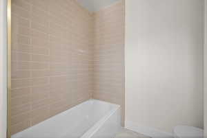 Full bath with a bath, baseboards, and toilet