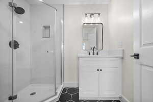 Bathroom featuring a stall shower, vanity, tile patterned floors, and baseboards