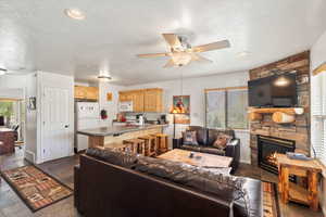 Living area with baseboards, a fireplace, ceiling fan, and a textured ceiling