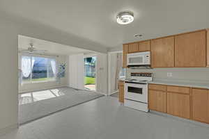 Kitchen featuring white appliances, light flooring, light countertops, a ceiling fan, and open floor plan