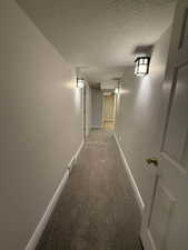 Hall with carpet flooring and a textured ceiling
