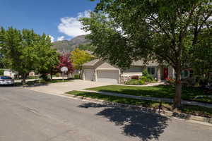 Obstructed view of property featuring a garage, a mountain view, driveway, a front yard, and stucco siding