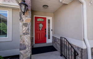 Entrance to property featuring stone siding and stucco siding