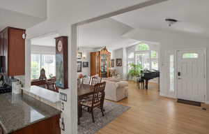 Dining space featuring light wood-type flooring, lofted ceiling, healthy amount of natural light, and a chandelier