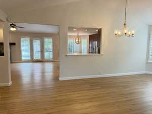 Unfurnished dining area with light wood finished floors, a chandelier, a ceiling fan, high vaulted ceiling, and recessed lighting
