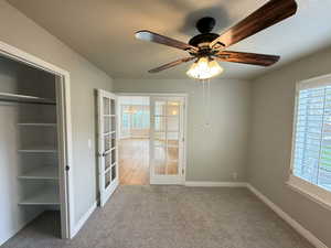 Unfurnished room with french doors, light colored carpet, and ceiling fan