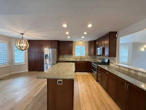 Kitchen with a chandelier, recessed lighting, decorative light fixtures, stainless steel appliances, and dark brown cabinets