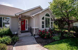 Entrance to property with stone siding, stucco siding, and roof with shingles