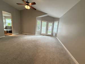 Carpeted empty room with vaulted ceiling and ceiling fan