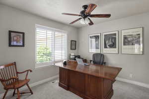 Home office featuring light carpet, ceiling fan, and baseboards