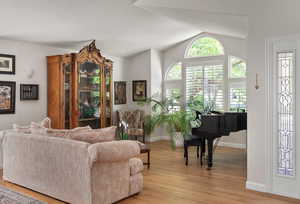 Living area with light wood-style flooring, lofted ceiling, and baseboards
