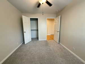 Unfurnished bedroom featuring light carpet, a closet, and ceiling fan