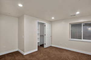 Unfurnished bedroom featuring carpet floors, baseboards, recessed lighting, and a walk in closet