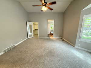 Unfurnished bedroom with a spacious closet, carpet, multiple windows, and vaulted ceiling