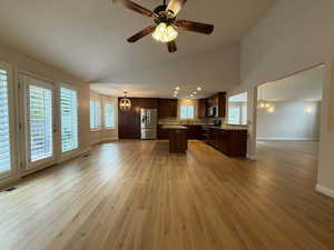 Kitchen featuring a chandelier, open floor plan, a center island, dark brown cabinetry, and high vaulted ceiling